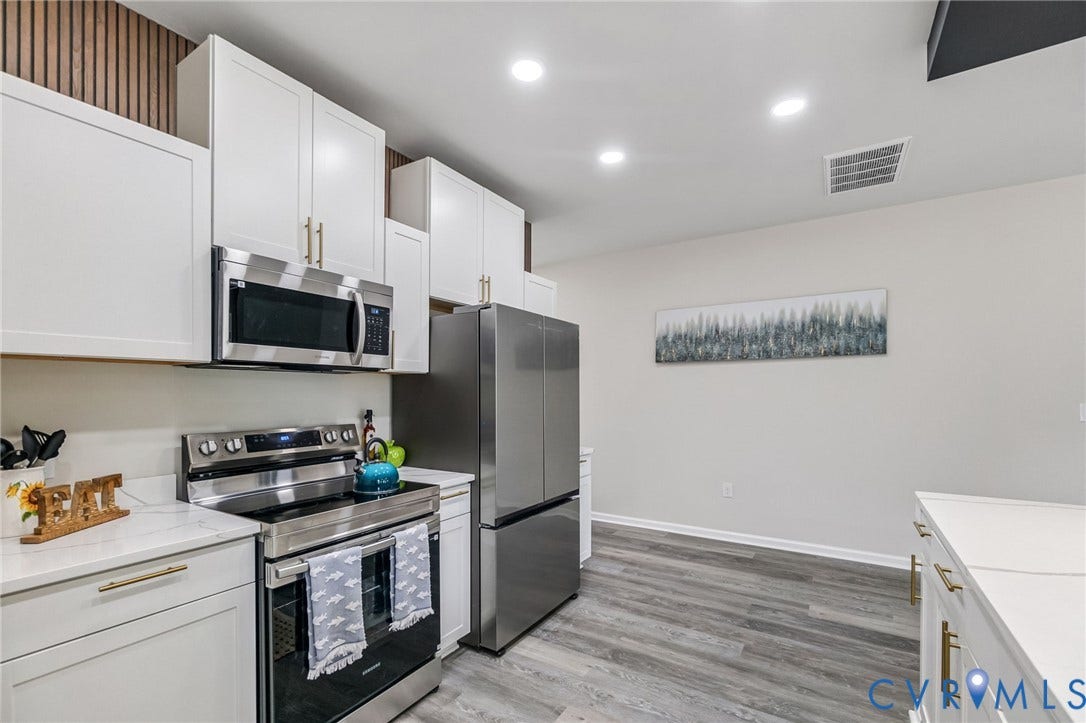 White cabinetry with gold-finish hardware, stainless steel appliances, wood-finish flooring, and recessed lighting