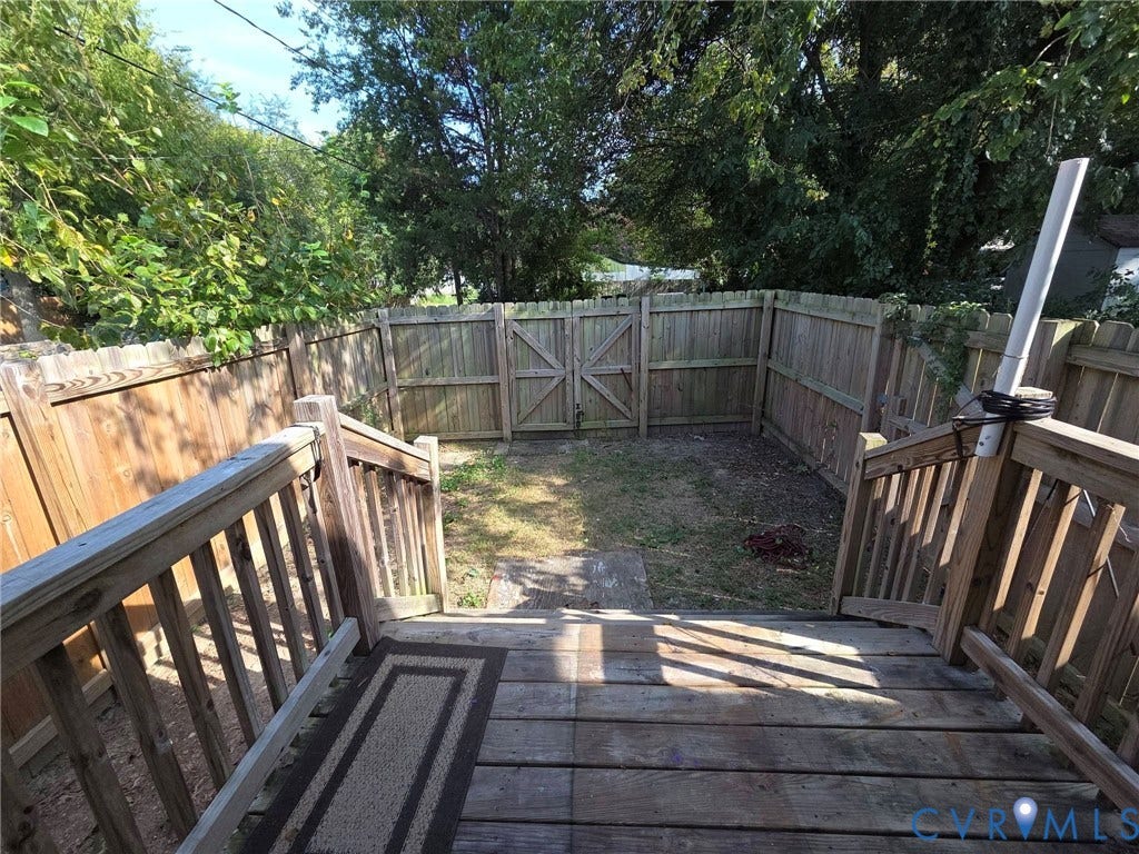 3400 Decatur Street, Richmond, VA 23224 Wood-finish deck with railings, descending to a fenced backyard featuring a grass area and a privacy fence with a gate