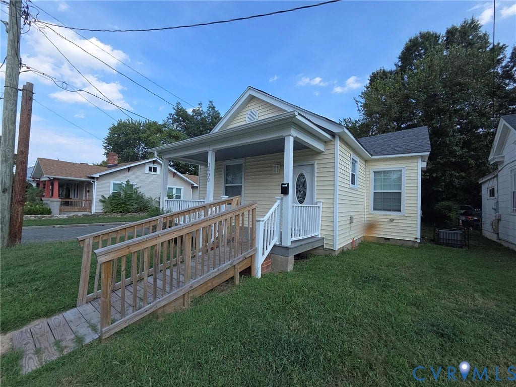 3400 Decatur Street, Richmond, VA 23224 Front exterior featuring light-colored siding, a covered porch with white railings, a front entry door with an oval glass insert, a wooden ramp leading to the porch, and a dark-shingled roof