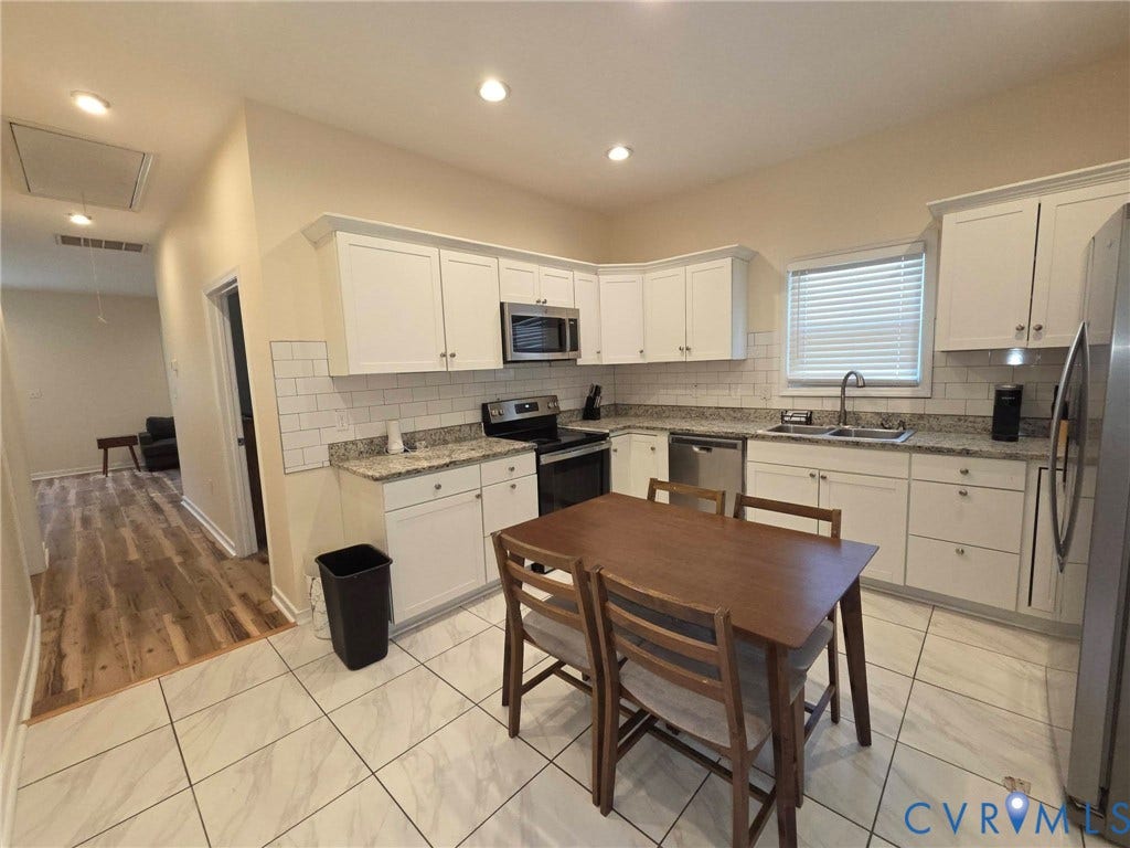 3400 Decatur Street, Richmond, VA 23224 White cabinetry, stone-finish countertops, stainless steel appliances, subway tile backsplash, and light-toned tile flooring