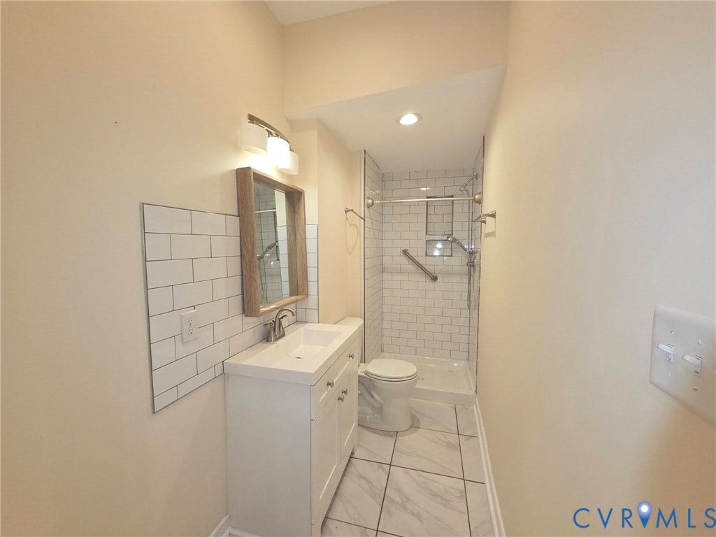 3400 Decatur Street, Richmond, VA 23224 White subway tile shower surround with a fixed showerhead and grab bar