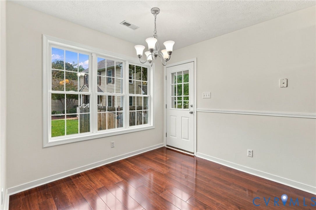 Wood-finish flooring, white trim, transom window door, wall-mounted lighting fixture, and chair rail molding