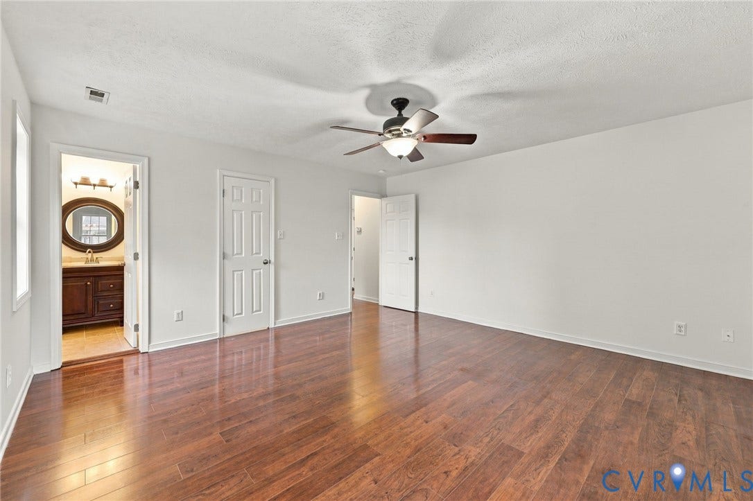Recessed ceiling fan, wood-finish flooring, white walls, paneled interior doors, and a bathroom vanity with an oval mirror and wall-mounted light fixture