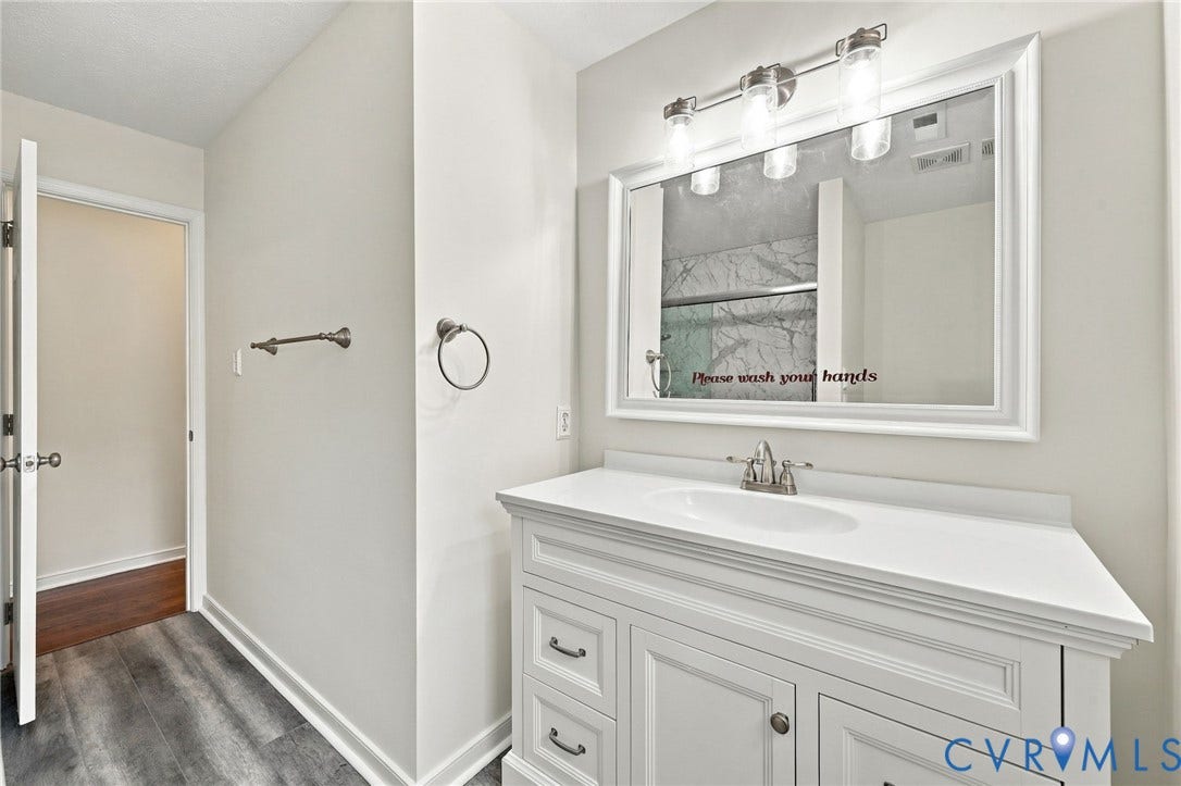 White vanity with integrated sink, brushed nickel faucet, and overhead vanity lighting