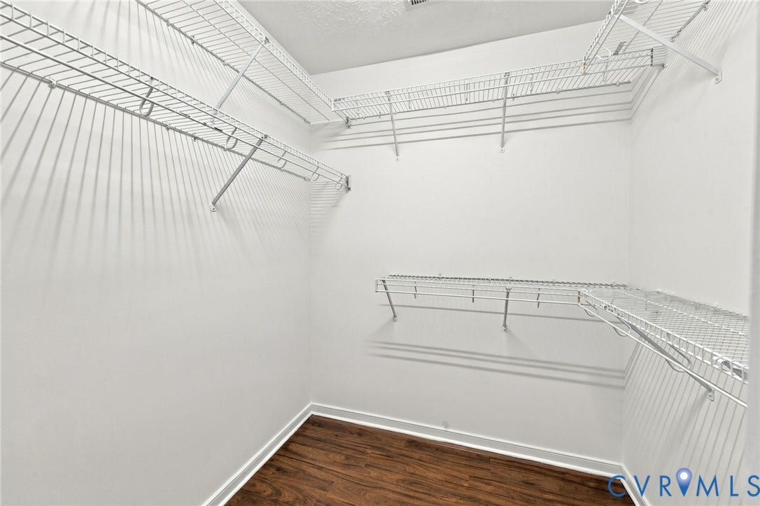 Walk-in closet featuring built-in wire shelving, white walls, and wood-finish flooring