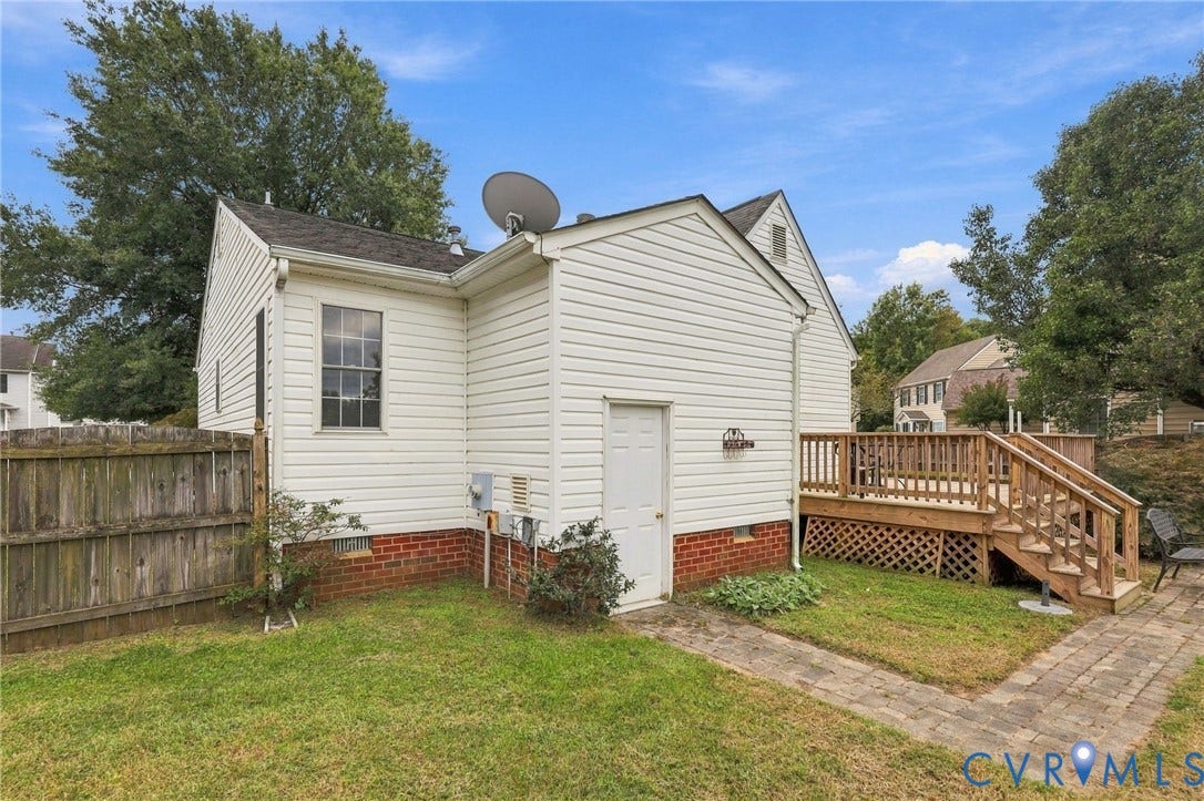 Expansive exterior deck with wooden railings, lattice skirting, and a matching staircase