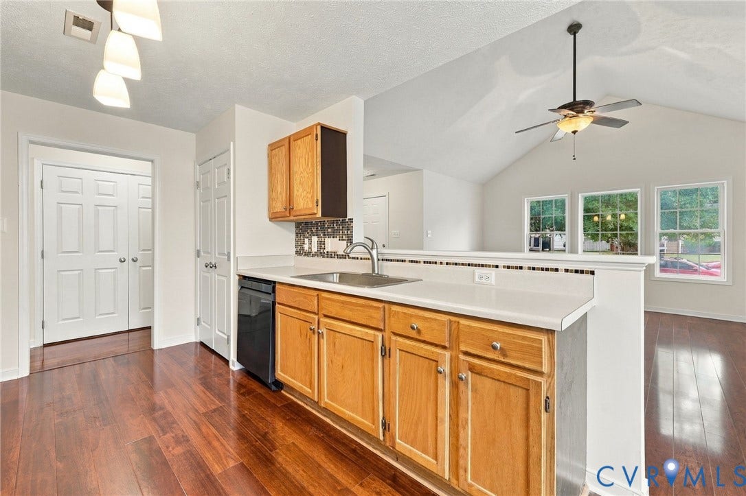 Kitchen featuring wood-finish cabinetry, light-toned countertops, and a tile backsplash