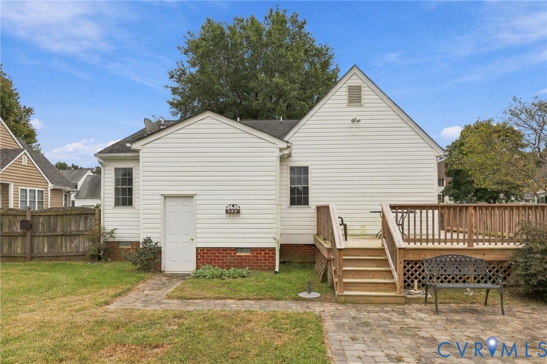 Expansive backyard featuring a large wood deck with stairs, a lattice skirt, and a paver patio
