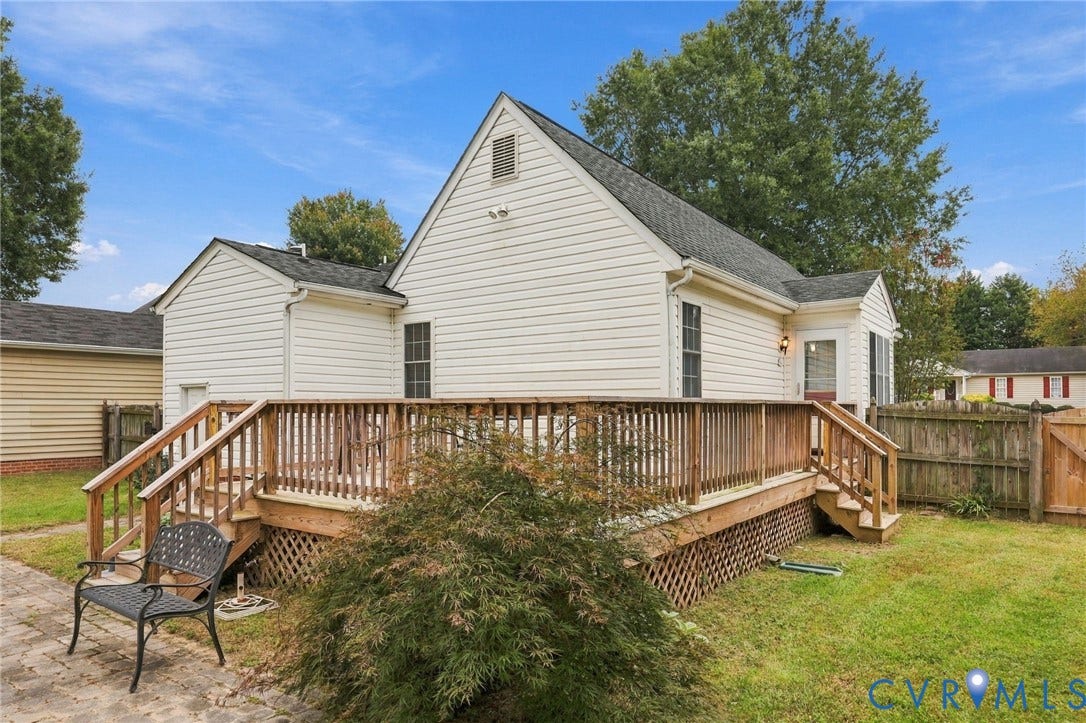 Expansive wood deck with lattice skirting and wood railings, featuring a grass lawn