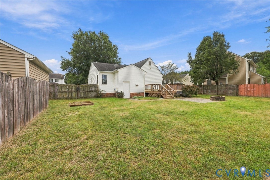 Expansive backyard featuring a wood deck, concrete patio, and a built-in fire pit
