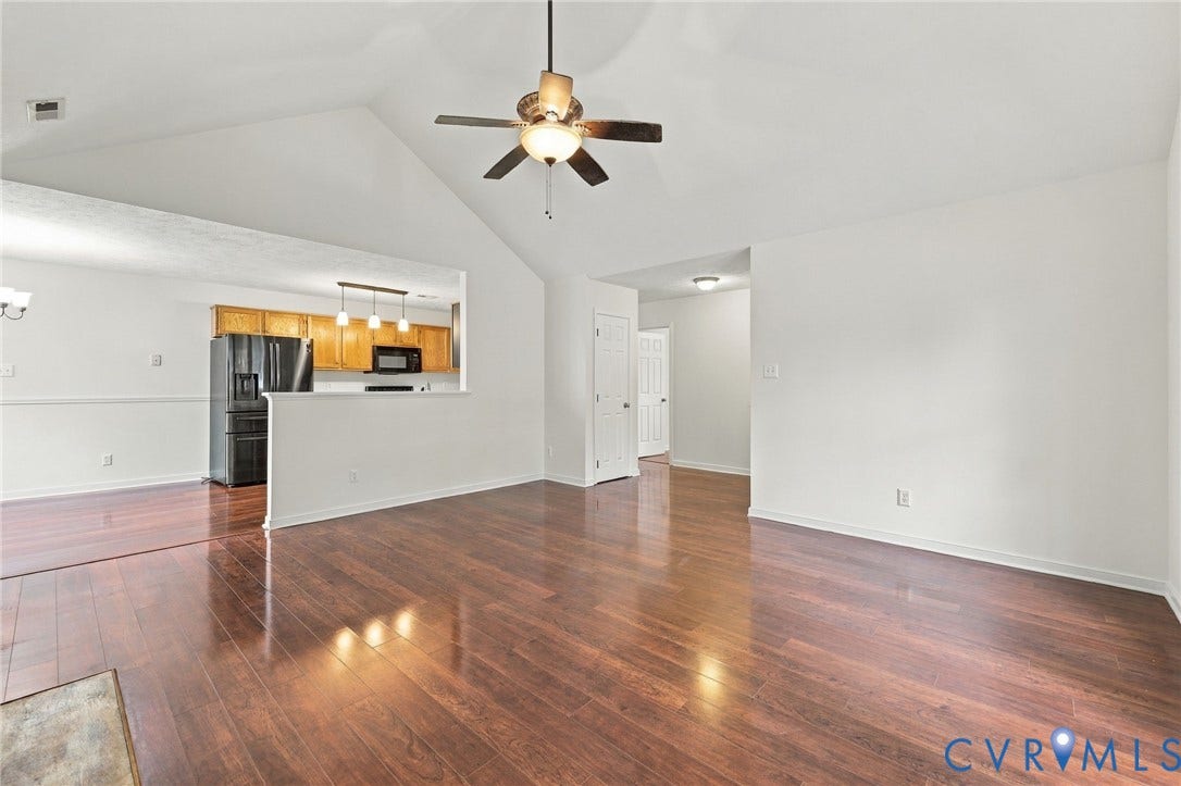 Vaulted ceiling, wood-finish flooring, ceiling fan with integrated lighting, recessed lighting, and a partial wall separating spaces