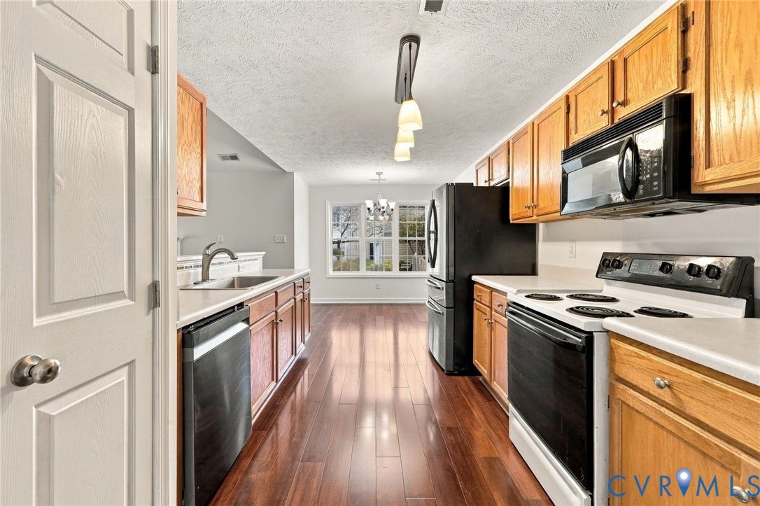 Kitchen featuring wood-finish flooring, a stainless steel sink, a dishwasher, a refrigerator, and an oven with a range hood