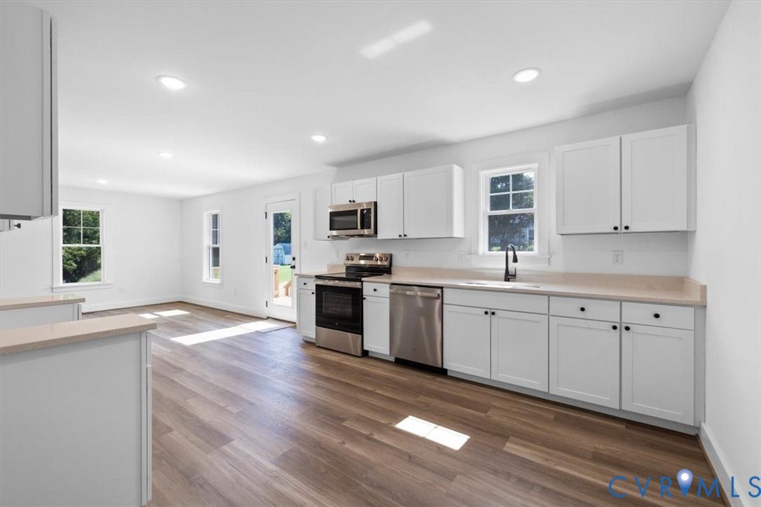 2242 Lakeview Drive, Powhatan, VA 23139 Kitchen featuring stainless steel appliances, white cabinetry with dark hardware, a single-basin sink with a matte black faucet, light-toned countertops, and wood-finish flooring