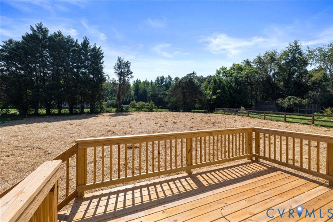 2242 Lakeview Drive, Powhatan, VA 23139 Expansive wooden deck with a slatted railing, overlooking a large open area with natural fencing and mature trees