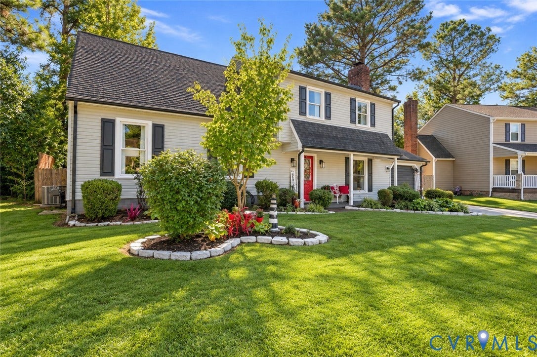 Two-story residence with light-toned siding, dark shutters, and a prominent front porch