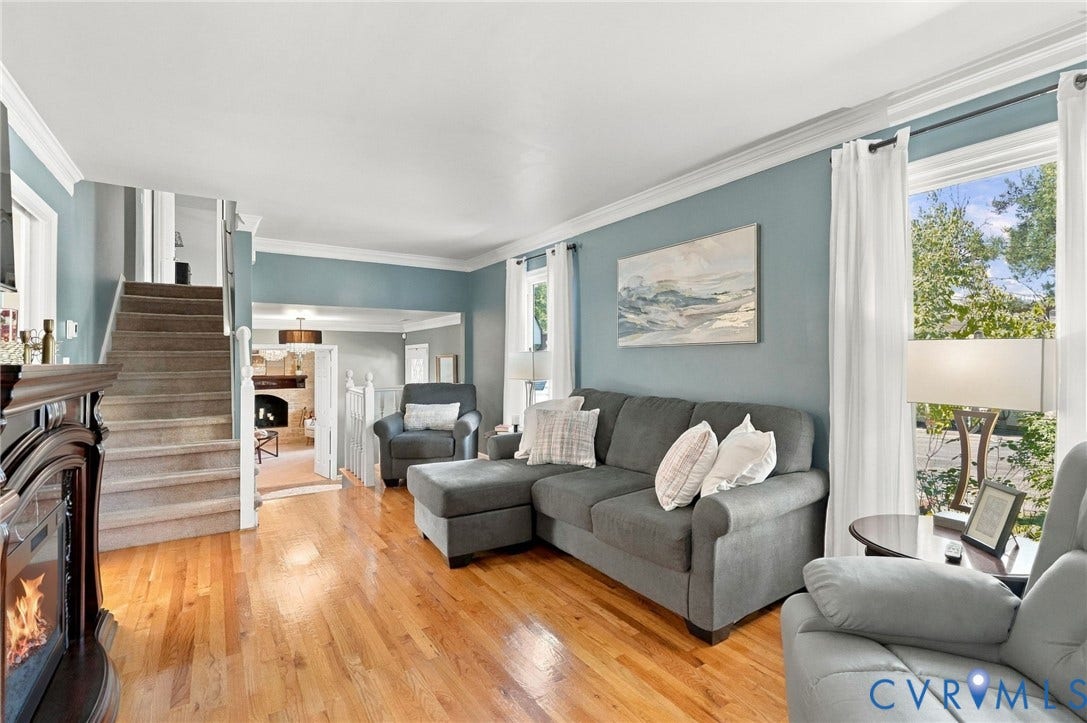 Hardwood flooring, crown molding, double windows with white trim, a built-in fireplace, and a carpeted staircase