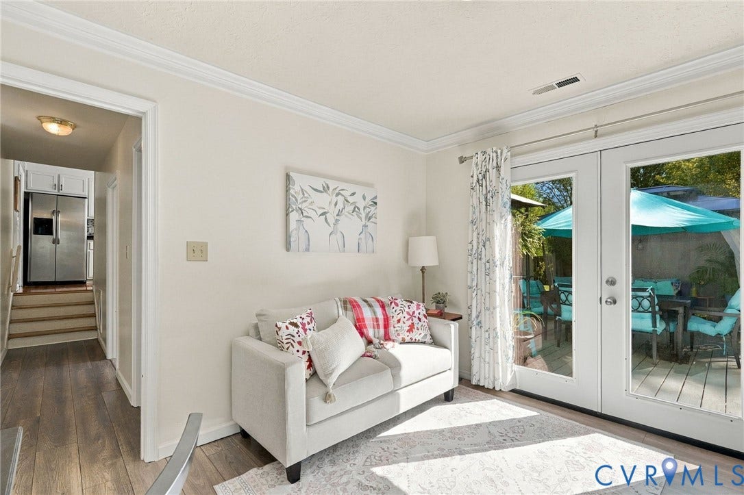Wood-finish flooring, crown molding, white double French doors, and a wood deck