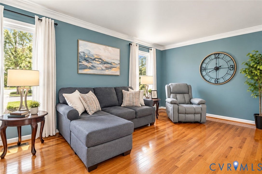 Hardwood flooring, painted walls, crown molding, and bright windows