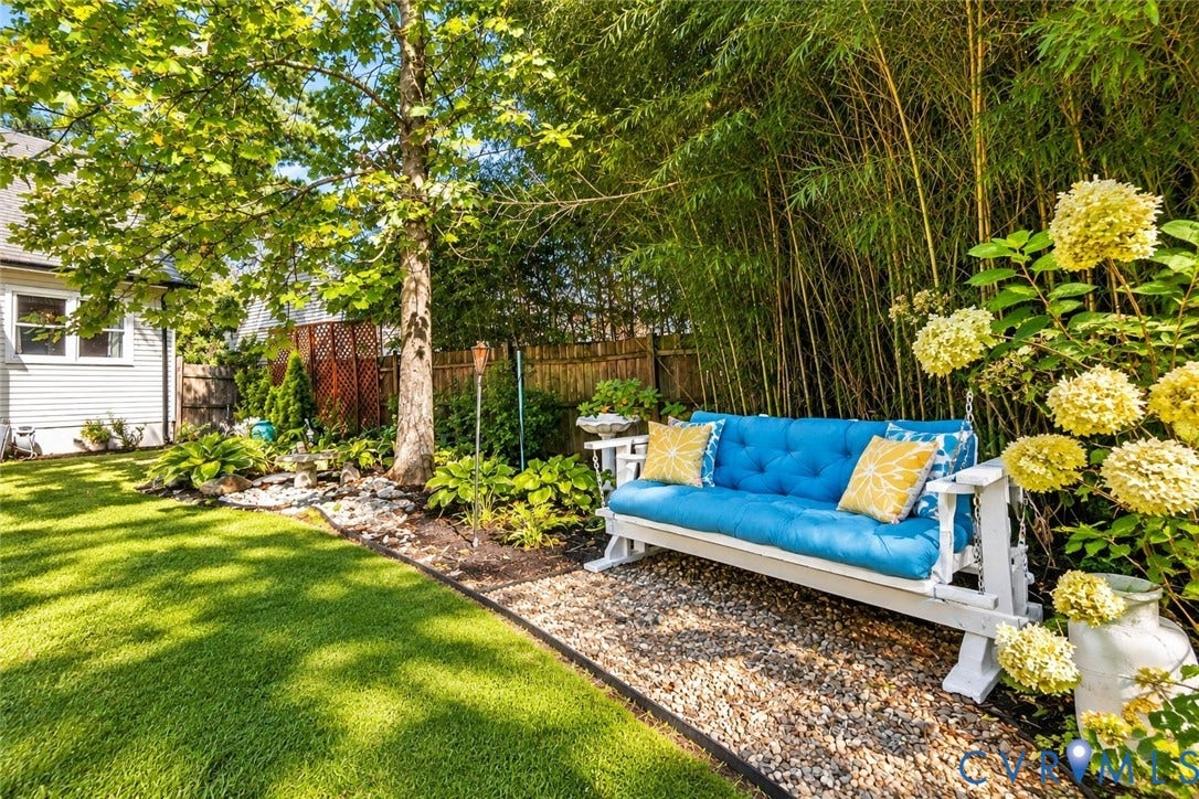 Expansive lawn area, mature trees, landscaped garden beds, gravel patio, privacy fencing