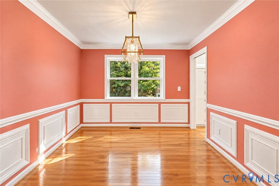 Hardwood flooring, picture frame wainscoting, crown molding, double window, and a bronze-finish chandelier