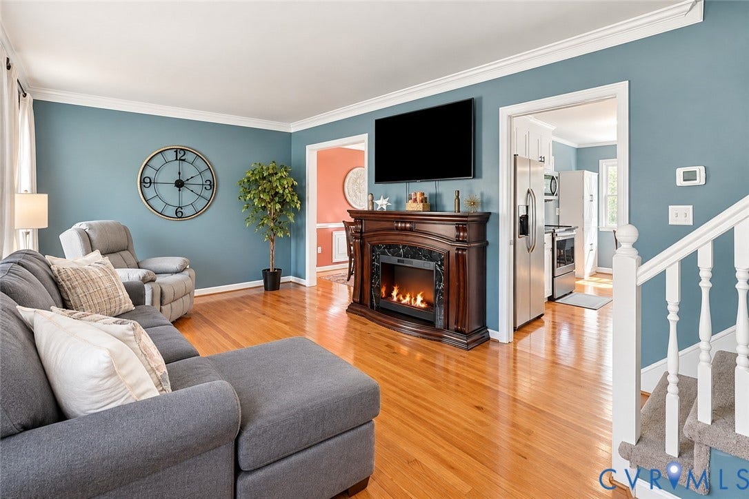 Hardwood flooring, crown molding, and a built-in electric fireplace with mantel