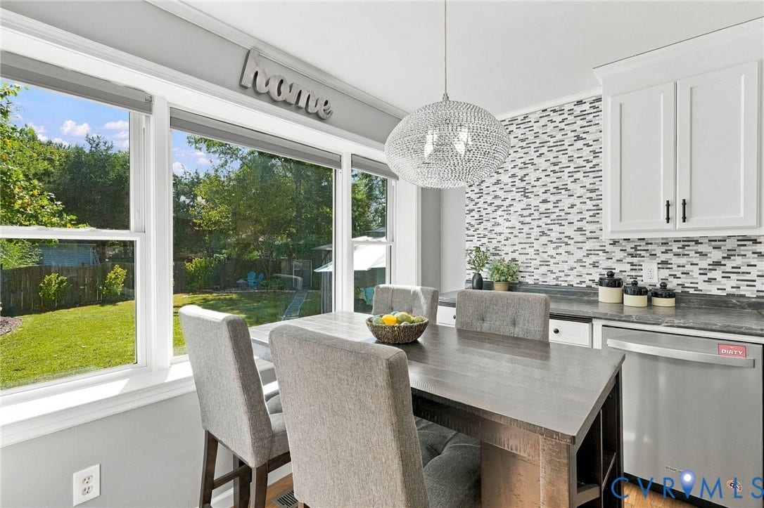 Built-in kitchen cabinetry, mosaic tile backsplash, countertop with integrated sink, stainless steel dishwasher, and a modern pendant light