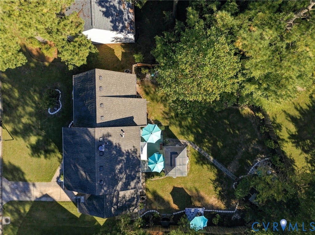 Spacious property featuring a large structure with a multi-gabled roof, extensive green lawn, mature trees, and a paved driveway