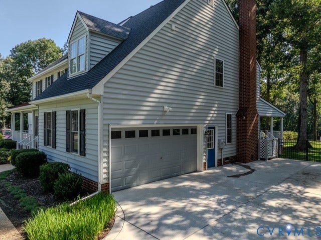 8113 Ainsdale Lane, Chesterfield, VA 23832 Traditional exterior with light blue siding, a two-car garage, a brick chimney, and a concrete driveway