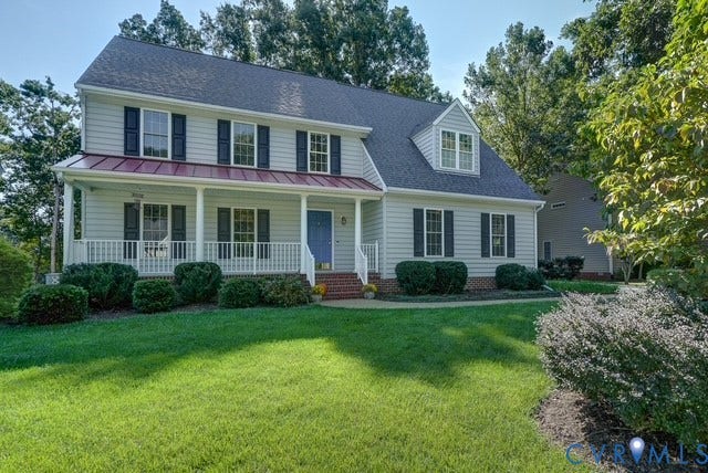 8113 Ainsdale Lane, Chesterfield, VA 23832 Traditional two-story residence featuring light-colored siding, dark shutters, a covered front porch with white railings, a prominent dormer window, and mature landscaping