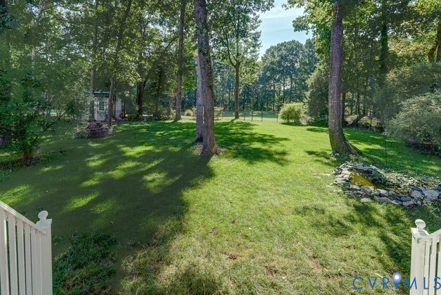 8113 Ainsdale Lane, Chesterfield, VA 23832 Expansive lawn with mature trees, a decorative rock-lined water feature, and a shed in the background