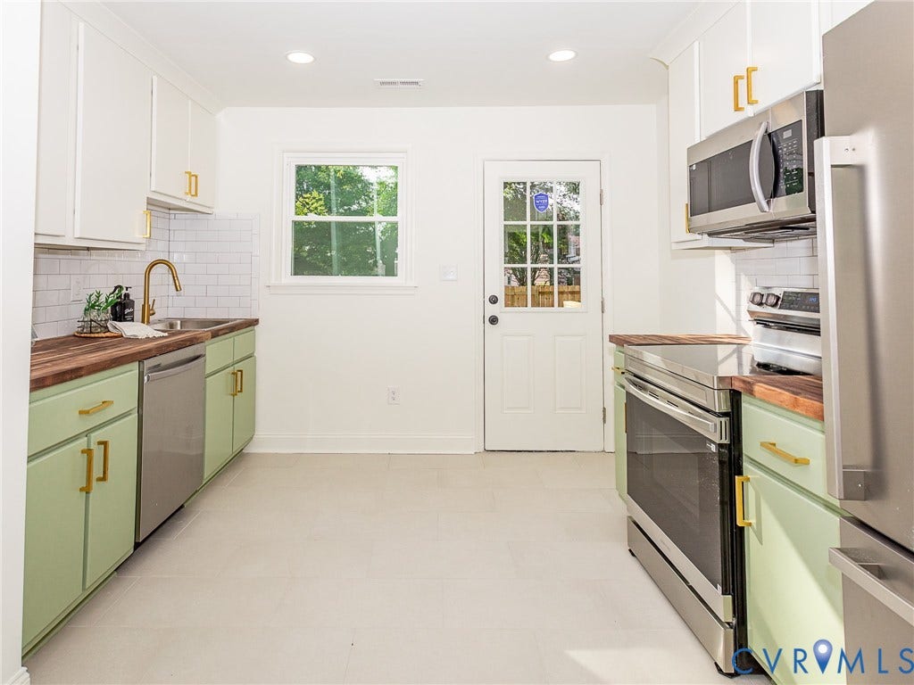 1601 N 25th Street, Richmond, VA 23223 Kitchen featuring light green and white cabinetry, wood-finish countertops, stainless steel appliances, and a subway tile backsplash
