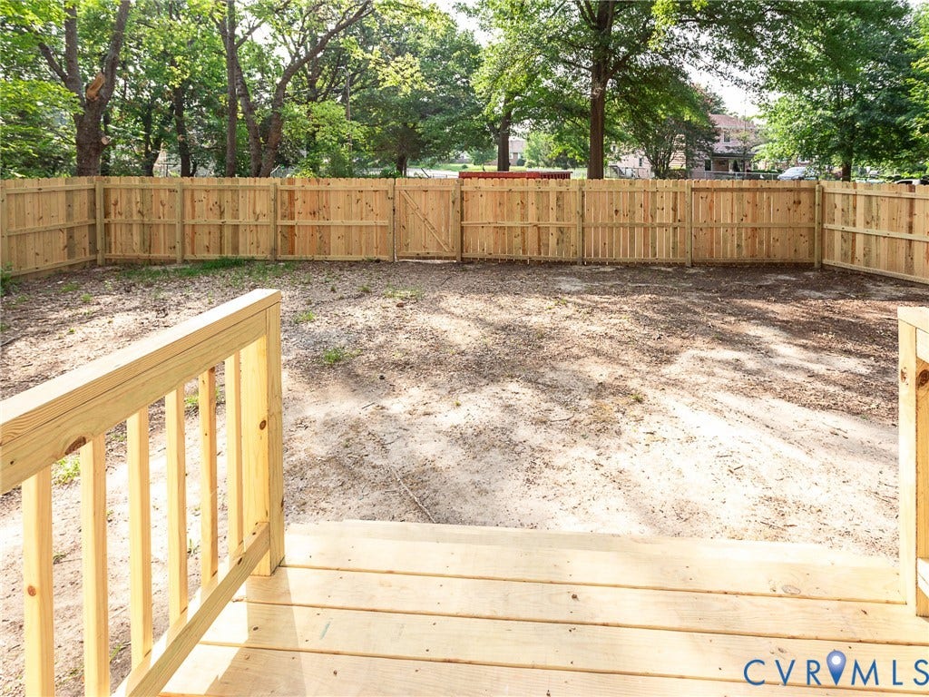 1601 N 25th Street, Richmond, VA 23223 Wood deck with railing overlooking a spacious backyard featuring a new privacy fence with gate