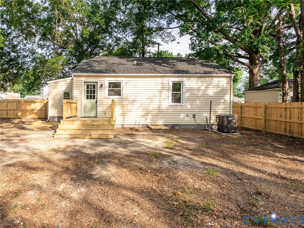 1601 N 25th Street, Richmond, VA 23223 Rear exterior featuring light vinyl siding, a new wooden deck, a light green door with glass panels, and a new privacy fence