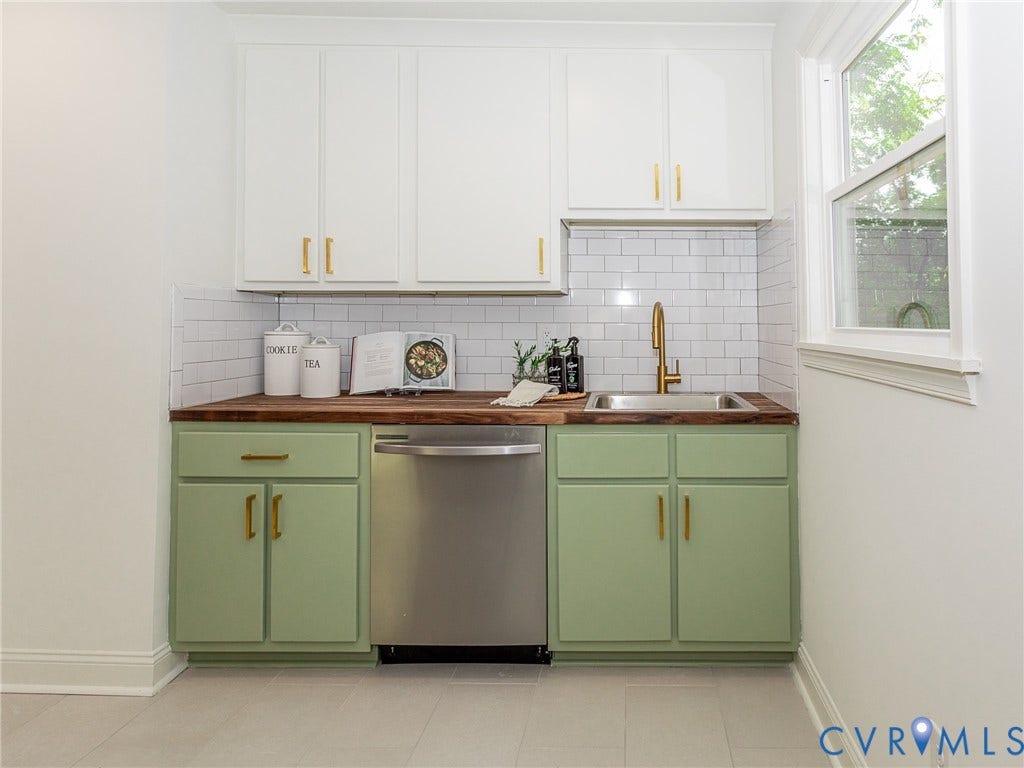 1601 N 25th Street, Richmond, VA 23223 White shaker-style upper cabinetry, wood-finish countertop, green lower cabinetry, stainless steel dishwasher, and a single basin sink with a gold-finish faucet