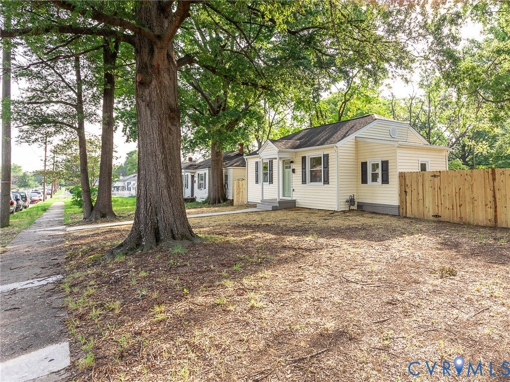 1601 N 25th Street, Richmond, VA 23223 Exterior featuring light-colored siding, dark window shutters, a white front porch with steps, and a newly installed wood fence