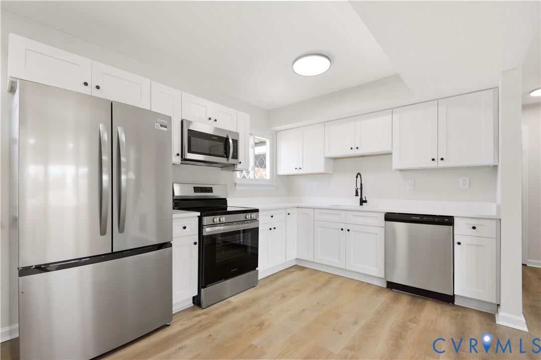 Kitchen featuring stainless steel appliances, white cabinetry, a matte black faucet, and wood-finish flooring