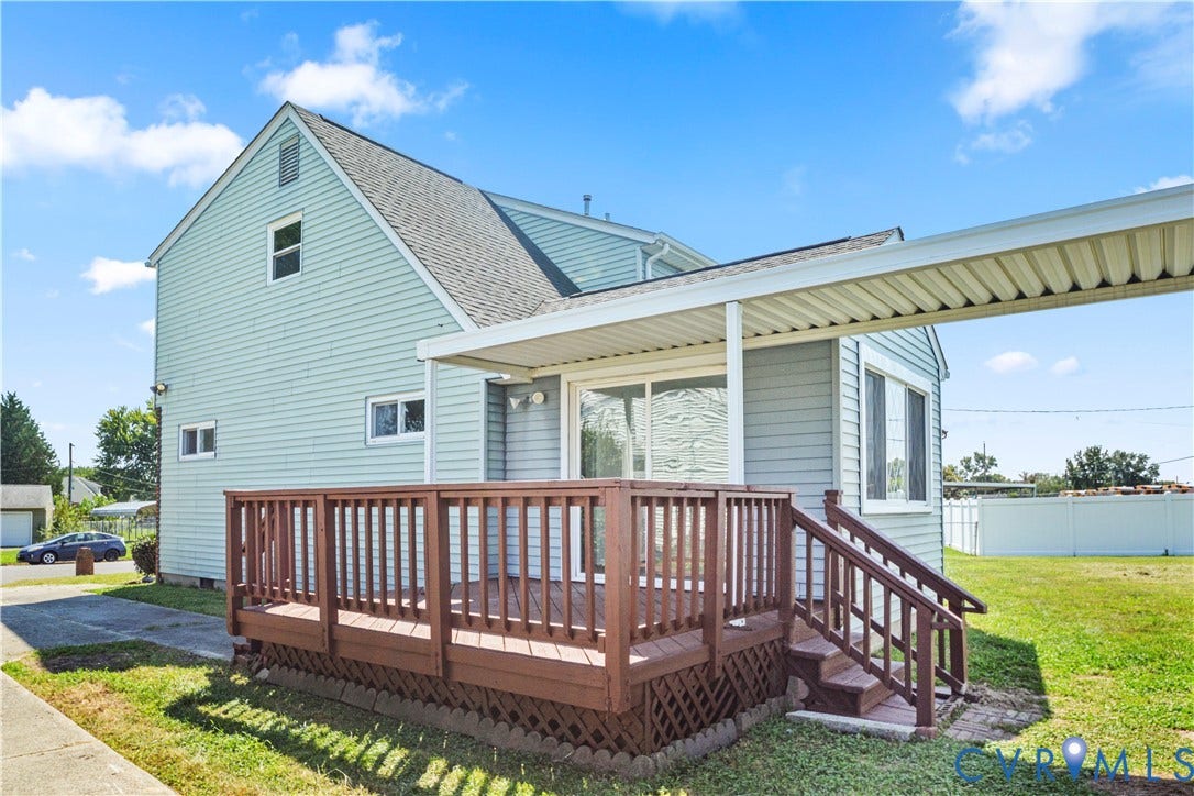 Exterior siding, gable roof, covered patio, wood deck with railing, and a grass lawn