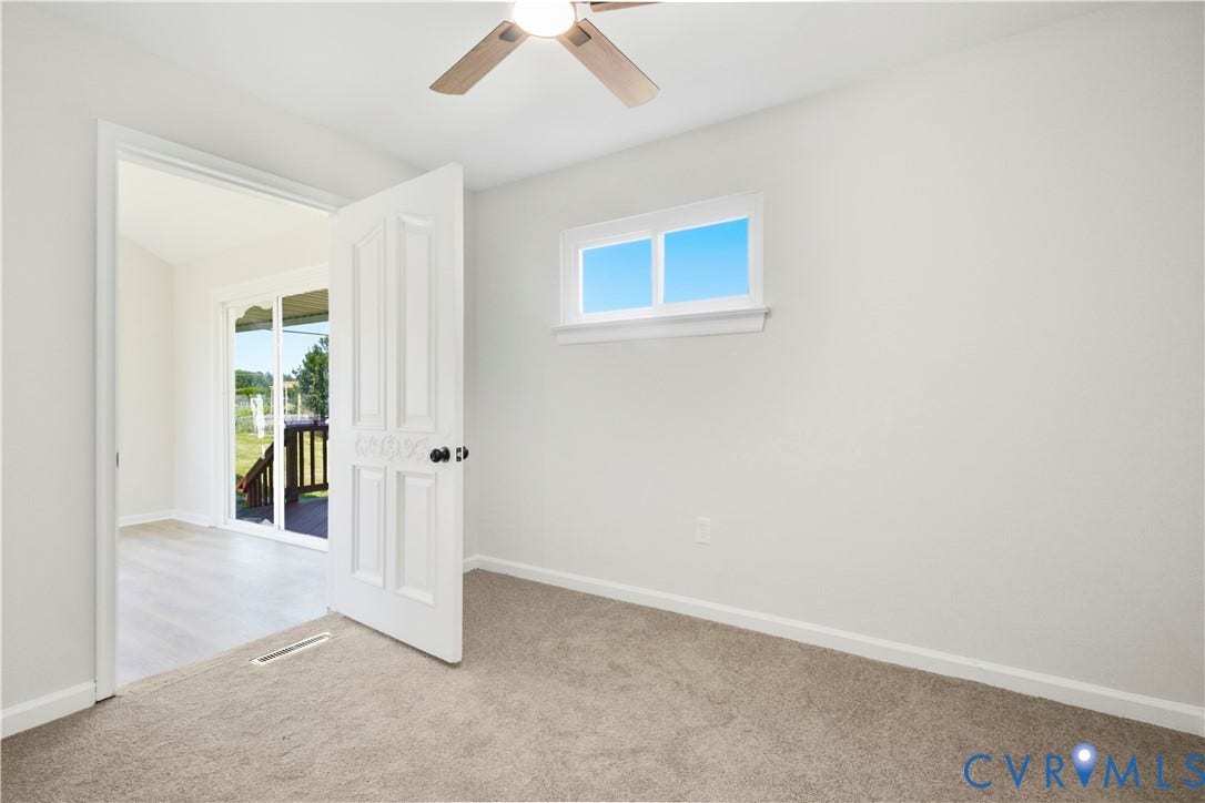 Carpeted flooring, ceiling fan with integrated lighting, and a white-framed window