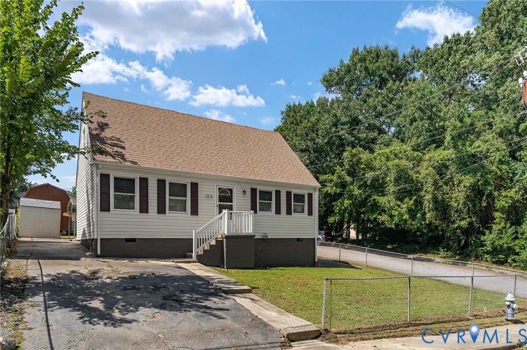 White siding exterior with brown window shutters, a front entry porch with white railings, and a brown shingle roof