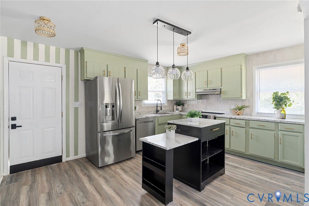 Kitchen featuring wood-finish flooring, green cabinetry, stainless steel appliances, a center island with a stone-finish countertop, and decorative pendant lighting