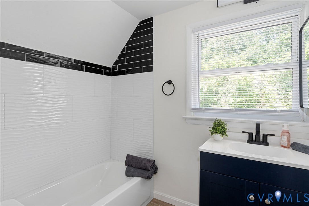 White wave-textured subway tile shower surround with contrasting black accent tiles