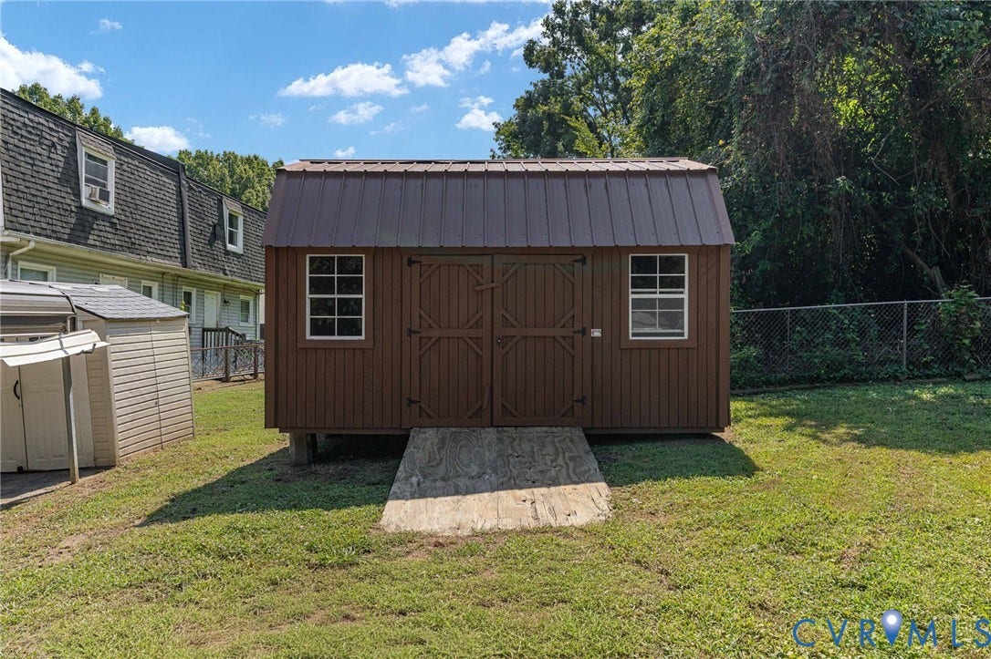 Wood-sided shed with a brown metal roof, dual front doors, and two windows