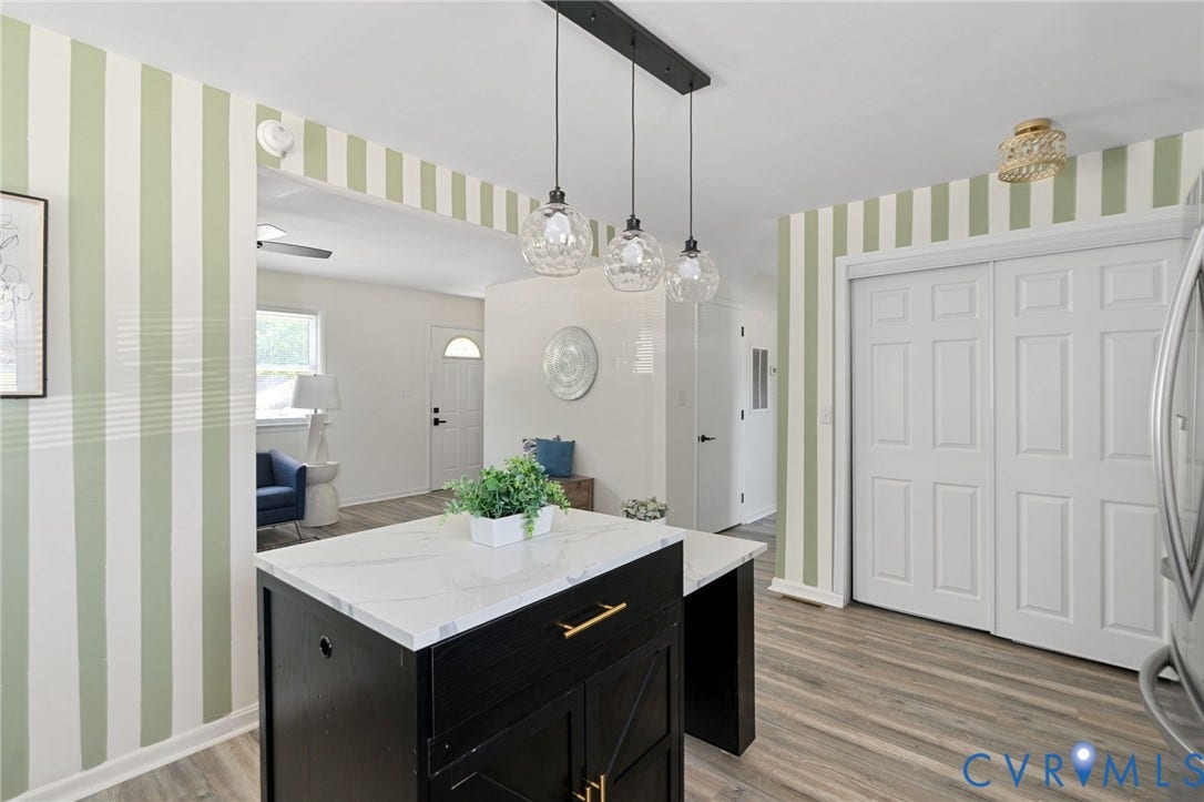 Central kitchen island with a white countertop and black base, accented by gold-finish hardware