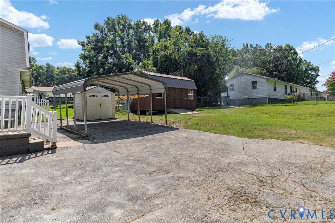 Carport with covered parking, storage shed, and additional outbuilding