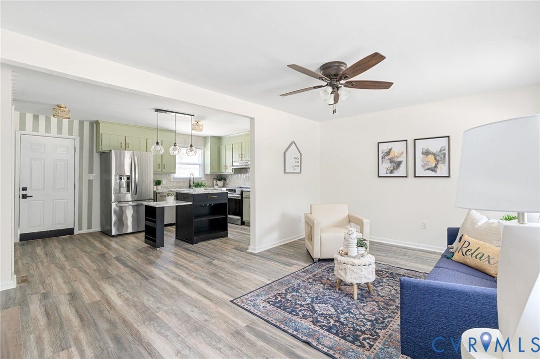 Open-concept living area featuring wood-finish flooring, a ceiling fan, and a kitchen with stainless steel appliances