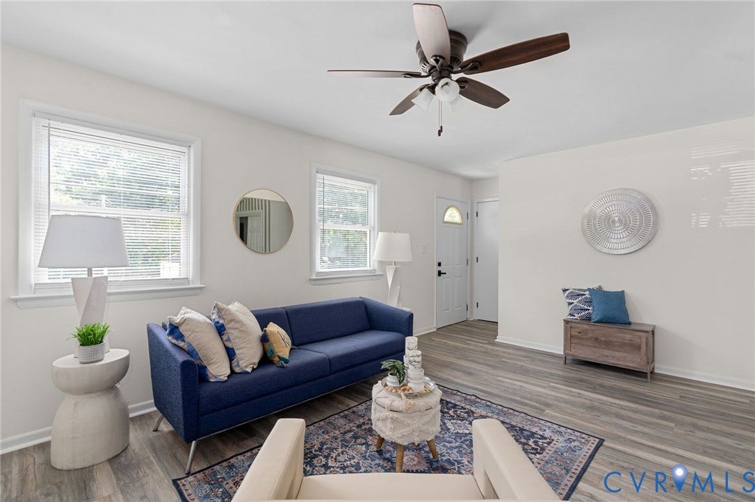Wood-finish flooring, white walls, multiple windows, and a ceiling fan with light fixture