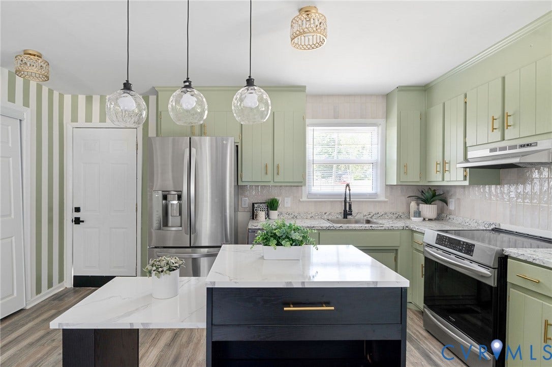 Kitchen featuring light green cabinetry, stainless steel appliances, a center island with a white countertop, pendant lighting, and wood-finish flooring