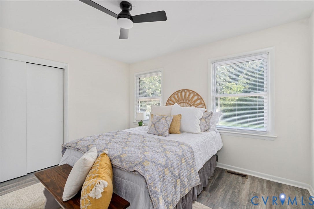 Neutral painted walls, two windows, ceiling fan, and wood-finish flooring
