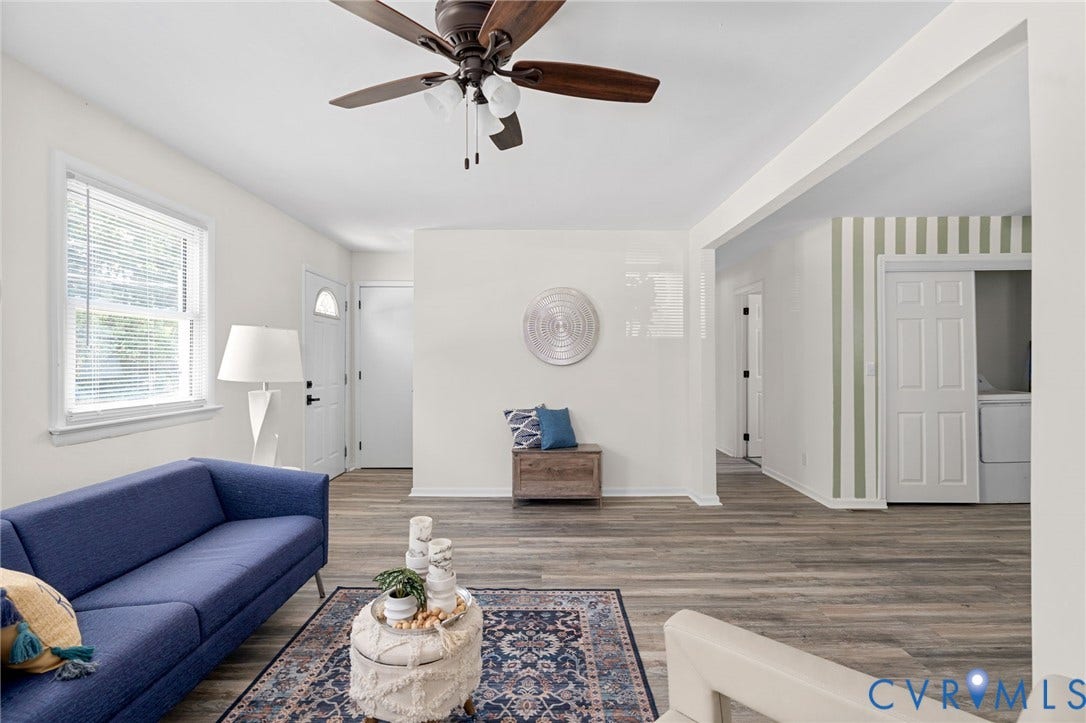 Wood-finish flooring throughout, white walls, and a ceiling fan with integrated lighting