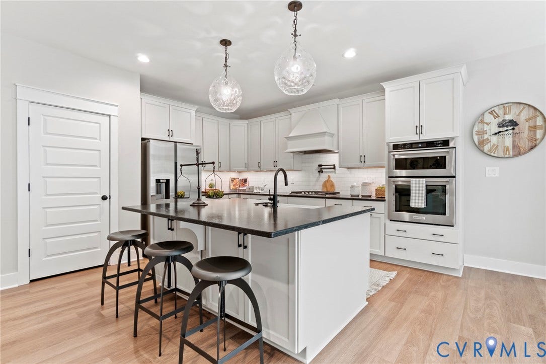 9143 Terroir Lane, Villas, New Kent, VA 23124 Bright kitchen featuring white cabinetry, a dark countertop island, stainless steel appliances, and wood-finish flooring